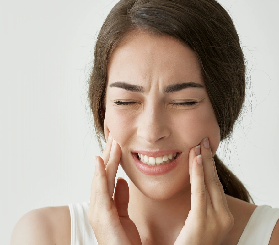 Woman touching face with hands, smiling against white background, dental care concept
