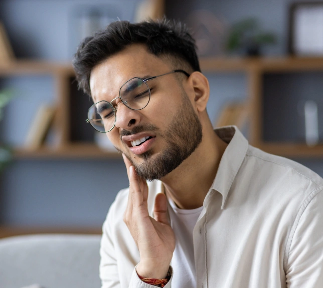 Man wearing glasses and white shirt smiling in modern dental office setting.